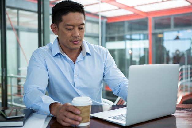 Homem de negócios usando laptop enquanto tomando café