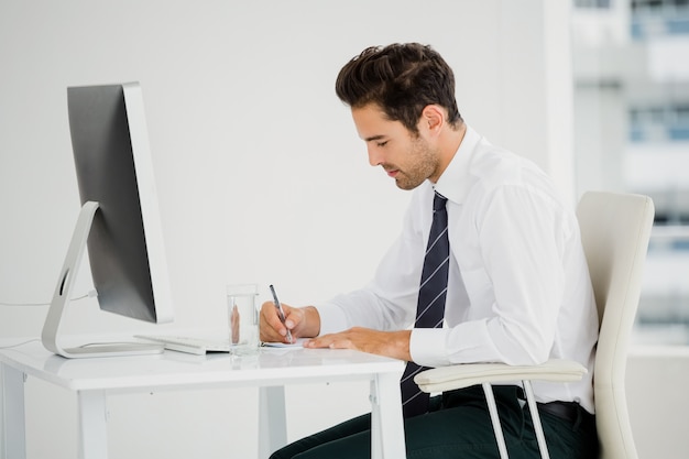 Homem de negócios usando o computador e tomar notas