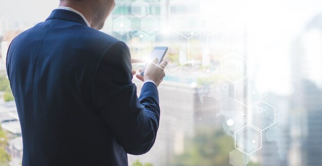 Homem de negócios usando o telefone inteligente na janela com forma de conexão de tecnologia futurista sobre o fundo da conexão de rede