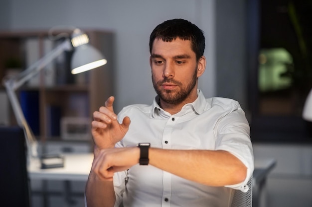 Foto homem de negócios usando relógio inteligente no escritório de noite