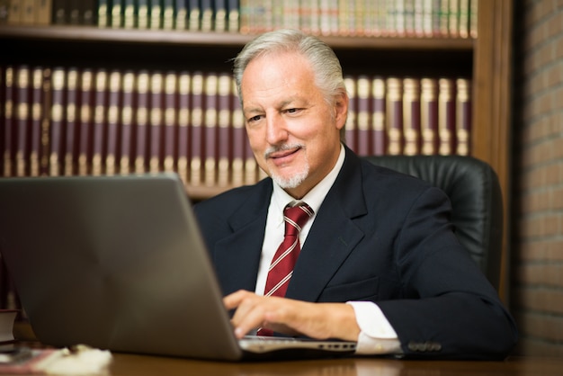 Homem de negócios usando seu laptop em uma biblioteca