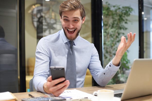 Homem de negócios usando seu telefone celular no escritório.