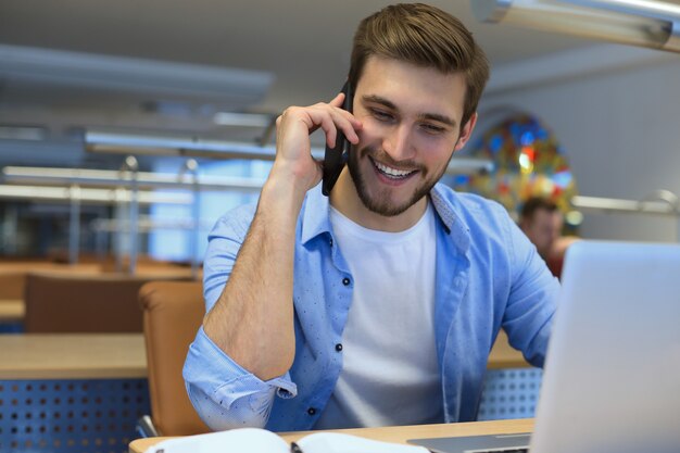 Homem de negócios usando seu telefone celular no escritório.