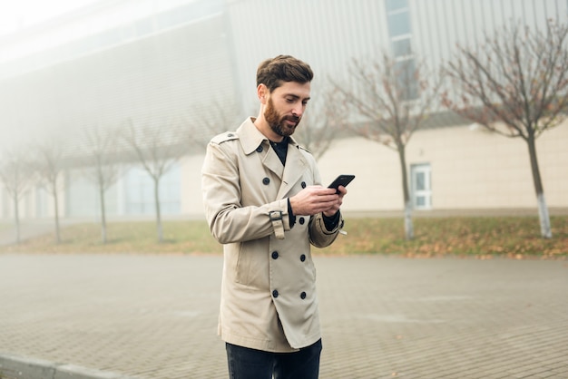 Homem de negócios usando smartphone enquanto caminhava