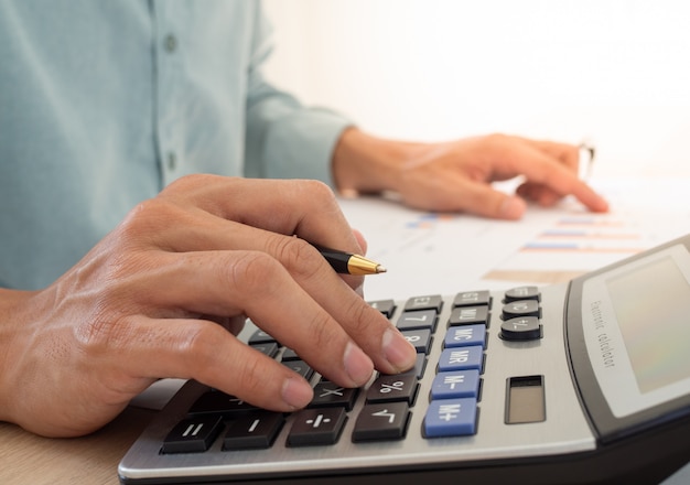 Homem de negócios usando uma calculadora para calcular as despesas de recibos colocados na mesa