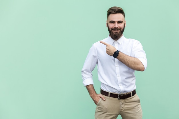 Homem de negócios vestindo camisa branca de pé apontando para um lado apresentando espaço de cópia para texto promocional