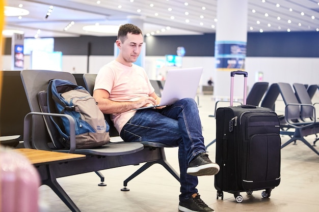 Homem de negócios, viajante europeu (passageiro) com smartphone e laptop na mão, aguarda o embarque (voo) no Aeroporto Internacional Havalimani de Istambul (Aeroporto IST)