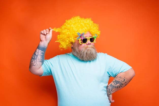 Homem de óculos de sol de pé contra um fundo laranja