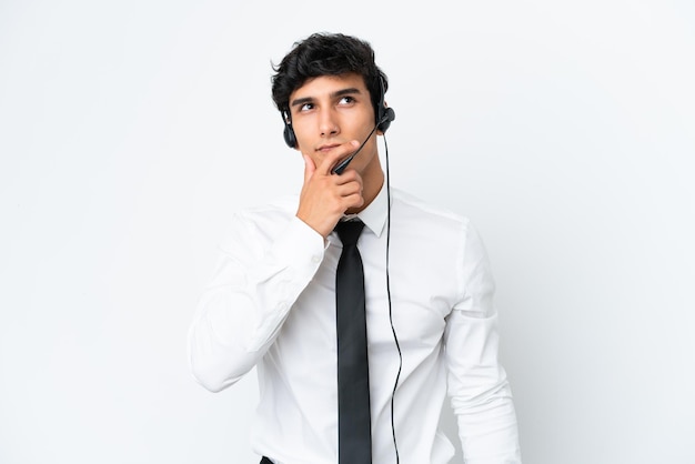 Homem de operador de telemarketing trabalhando com um fone de ouvido isolado no fundo branco, tendo dúvidas e com expressão facial confusa