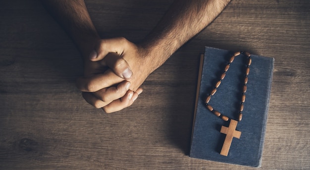 Foto homem de oração e cruz de madeira na bíblia sobre a mesa