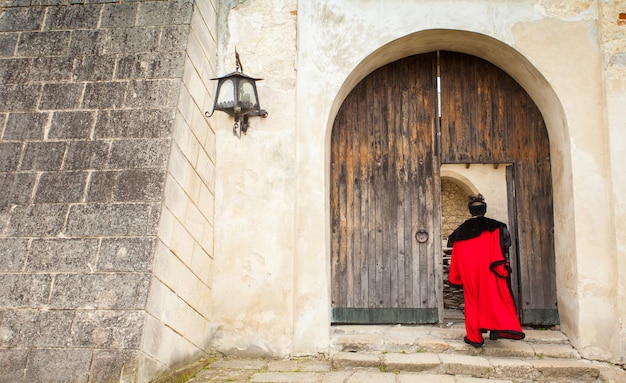 Homem de pano antigo entra na porta de madeira aberta do velho castelo