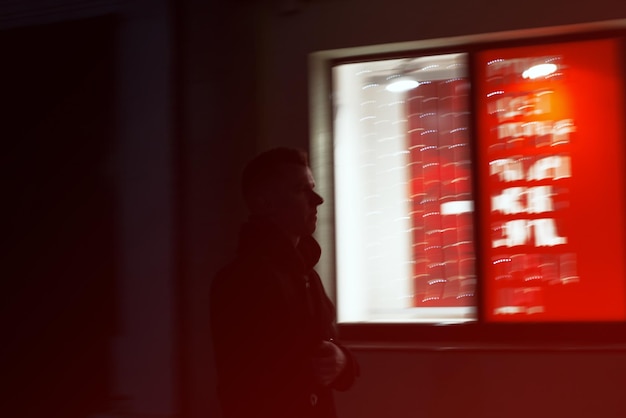 Foto homem de pé à janela no quarto escuro