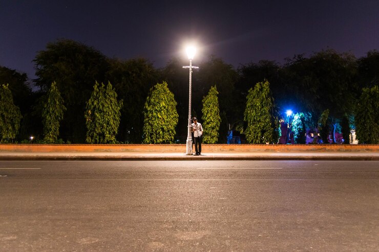 Foto homem de pé ao lado da luz da rua à noite