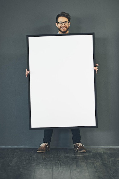 Homem de pé com um sinal em branco ou moldura de retrato mostrando espaço de cópia para publicidade ou marketing com fundo escuro Cara sorridente e inteligente feliz segurando grande cartaz branco ou copyspace de página