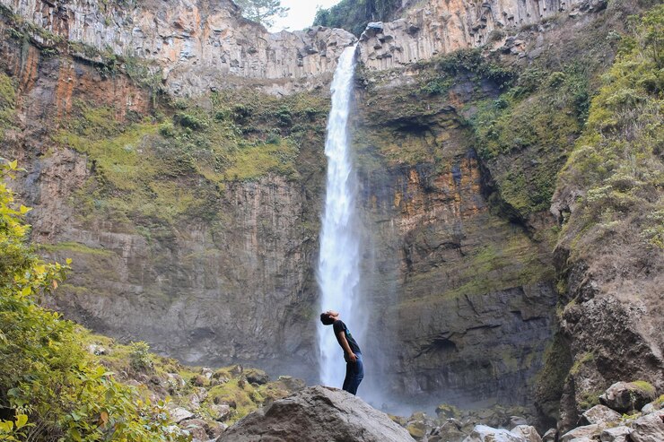 Foto homem de pé contra a cachoeira
