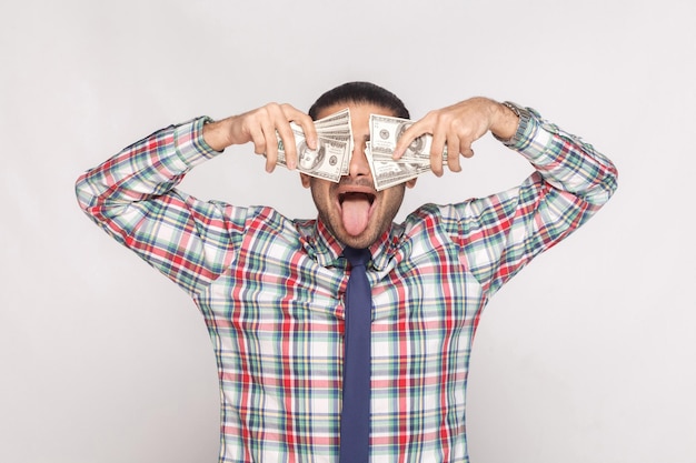 Foto homem de pé e cobrindo os olhos com leque de dinheiro com língua de fora