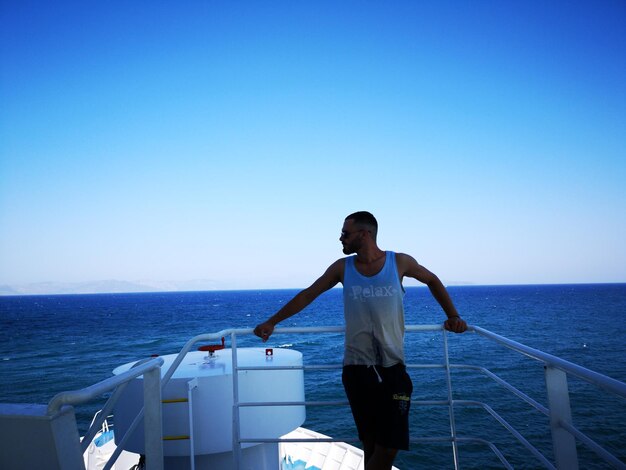 Foto homem de pé em um barco contra um céu azul claro