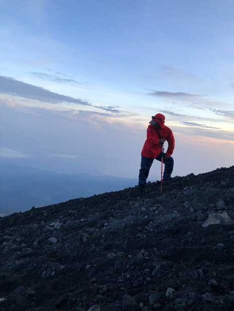 Foto homem de pé em uma rocha contra o céu durante o pôr do sol