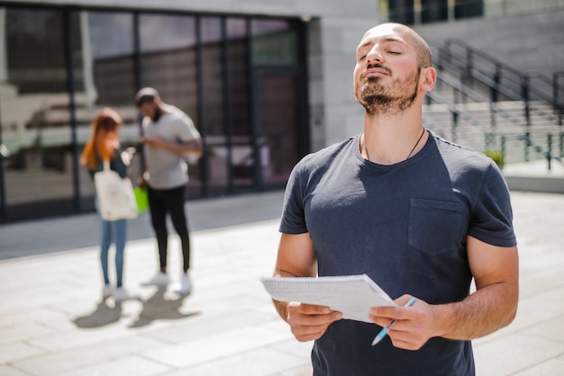 Homem de pé fora segurando notepad meditando