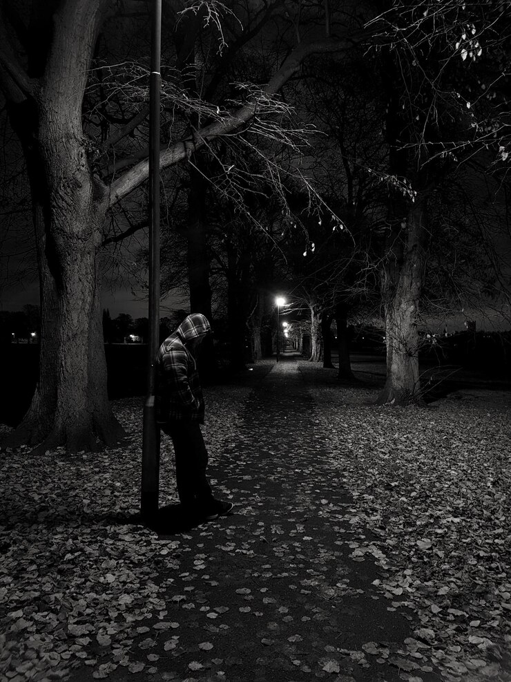 Foto homem de pé na calçada no parque durante a noite