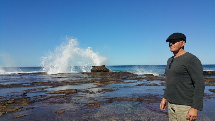 Foto homem de pé na praia contra o céu azul claro em um dia ensolarado