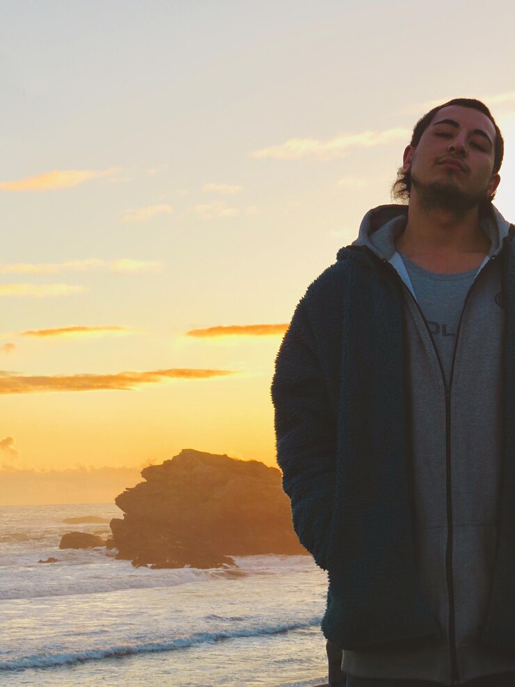 Foto homem de pé na praia contra o céu durante o pôr do sol