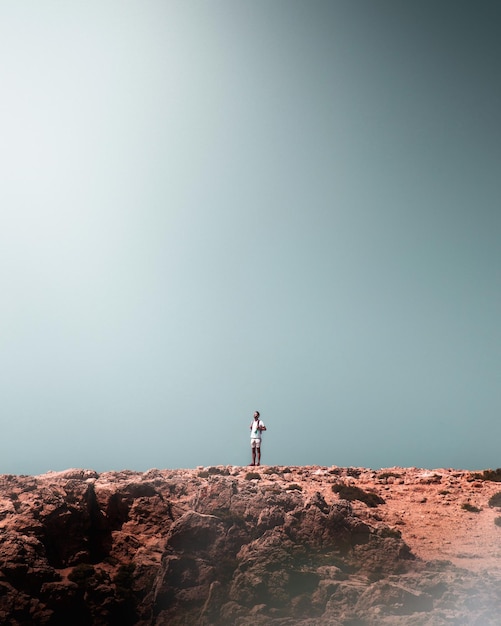 Foto homem de pé na rocha contra o céu