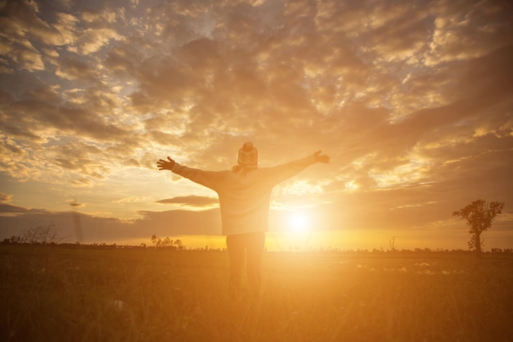 Foto homem de pé no campo contra o céu durante o pôr do sol
