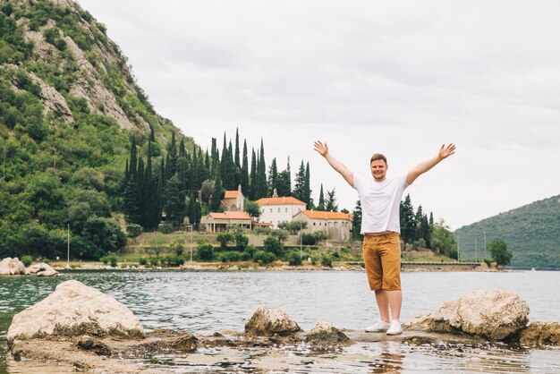 Homem de pé no penhasco com bela vista do mar e montanhas