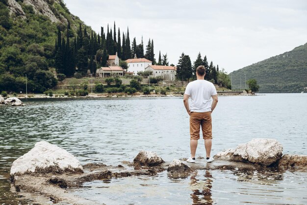 Homem de pé no penhasco com bela vista do mar e montanhas