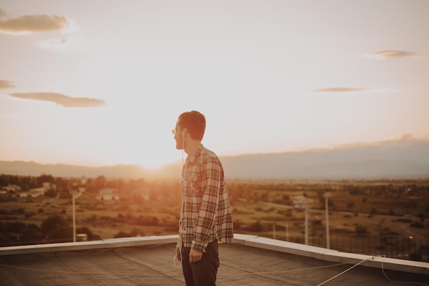 Foto homem de pé no terraço contra o céu durante o pôr do sol