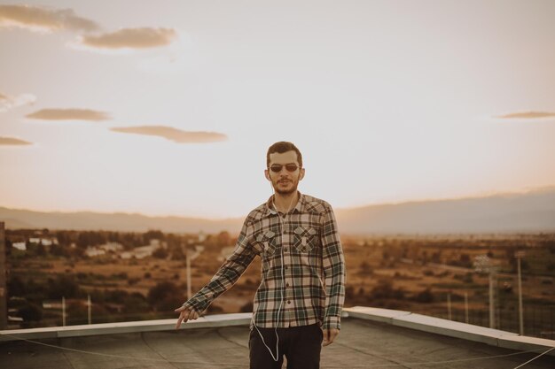 Foto homem de pé no terraço contra o céu durante o pôr do sol