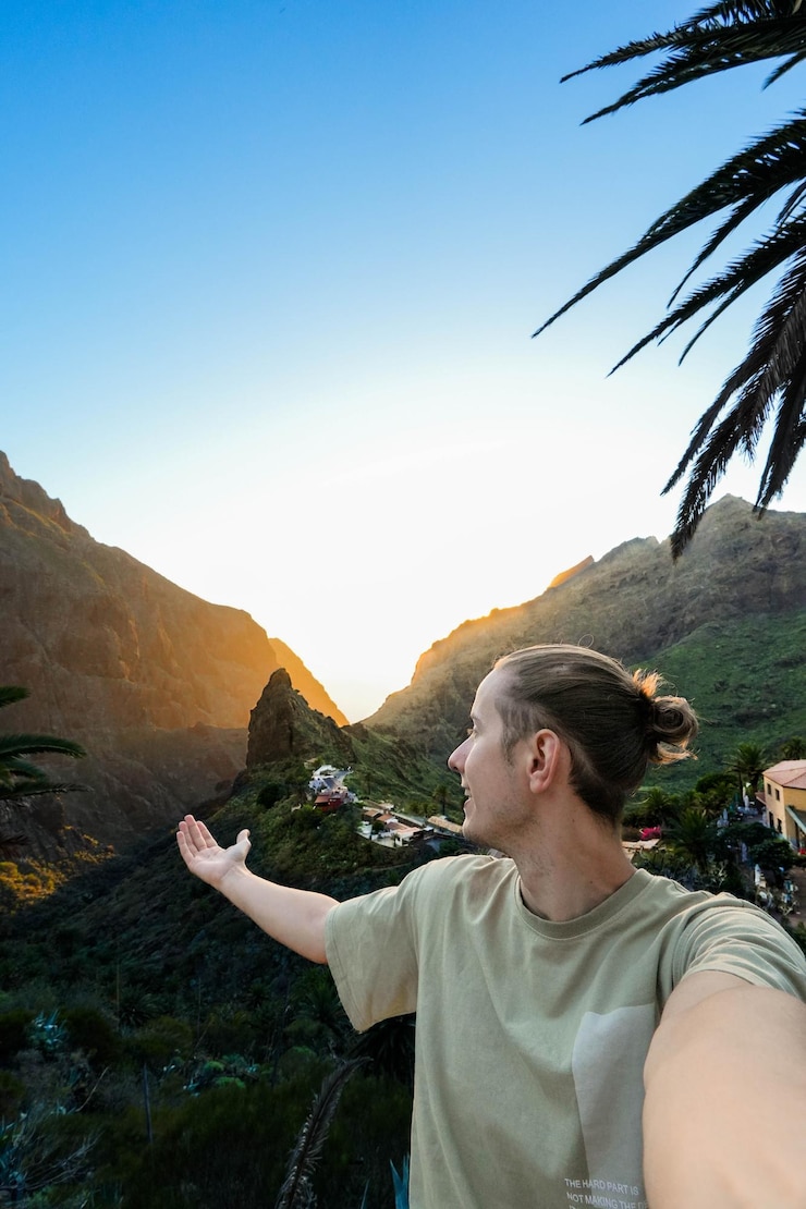 Foto homem de pé no topo de uma colina verde e exuberante no vale de masca, em tenerife