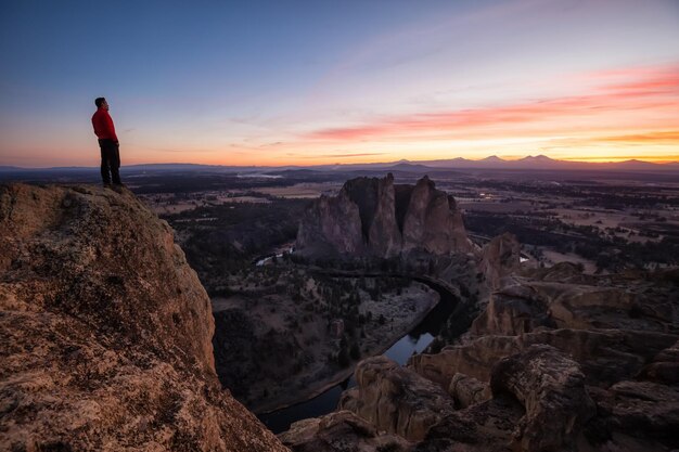 Homem de pé no topo de uma montanha está desfrutando de uma paisagem