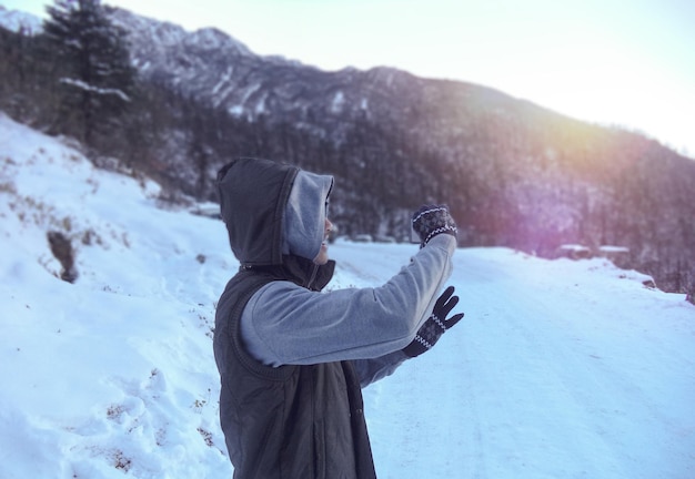 Homem de pé numa montanha coberta de neve contra o céu