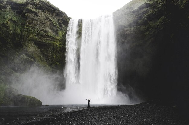 Foto homem de pé perto da cachoeira