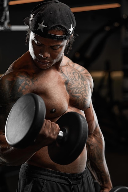 Homem de pele escura forte e musculoso treina em equipamentos modernos no ginásio Retrato de treinador de fitness muscular bombeado