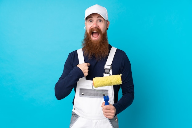 Homem de pintor com barba longa sobre azul isolado comemorando uma vitória