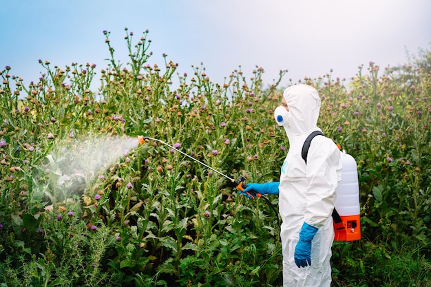 Foto homem de roupa de trabalho protetora pulverizando herbicida em plantas