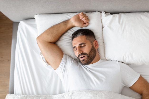 Foto homem de roupas casuais está dormindo descansando em um quarto moderno