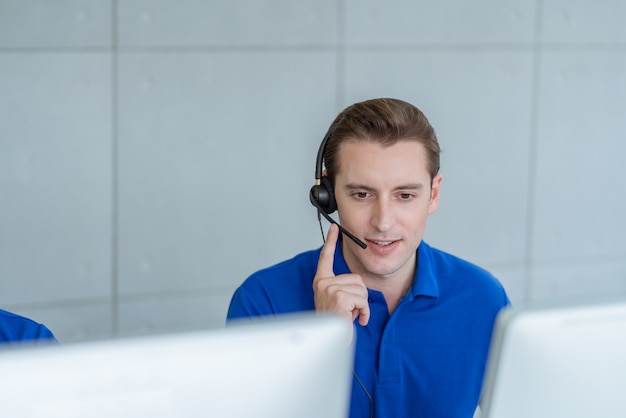 Homem de serviço ao cliente usando fone de ouvido conversando com o cliente no escritório do centro de chamada