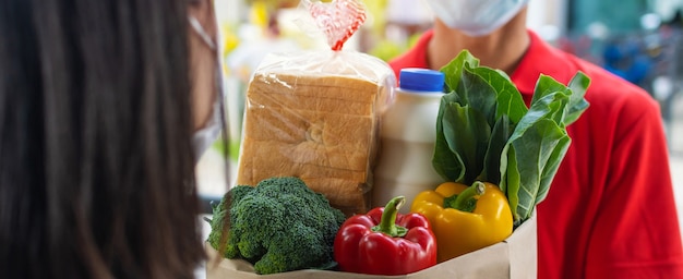 homem de serviço de entrega de comida usando máscara de proteção e entregando saco de conjunto de comida fresca