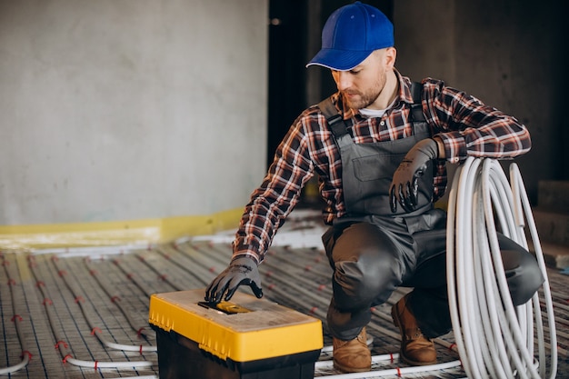 Homem de serviço instalando o sistema de aquecimento da casa sob o piso