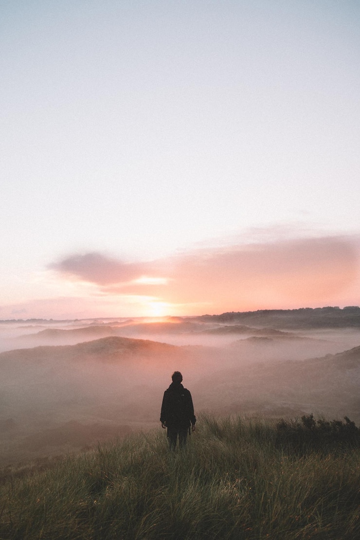 Foto homem de silhueta caminhando no campo contra o céu durante o pôr do sol