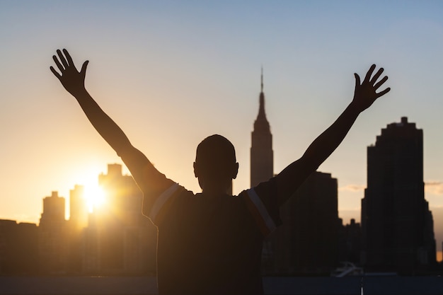 Homem de sucesso com o skyline de Nova York em segundo plano ao pôr do sol