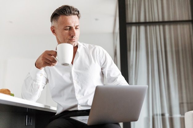 Homem de sucesso vestido com roupas formais usando laptop