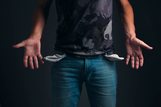 Homem de T-shirt e jeans com bolsos vazios Conceito de falência e pobreza