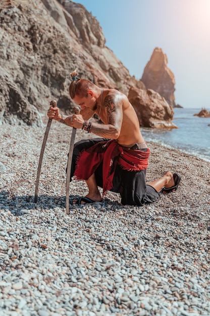 Homem de tatuagem maduro segurando espadas prontas para lutar no retrato de fundo do mar de um bonito
