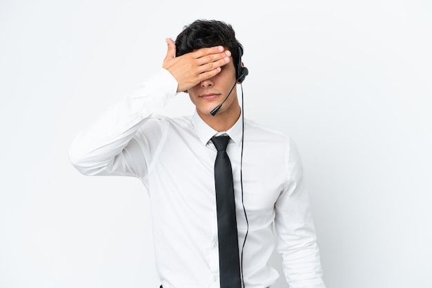 Homem de telemarketing trabalhando com um fone de ouvido isolado no fundo branco, cobrindo os olhos pelas mãos. Não quero ver algo