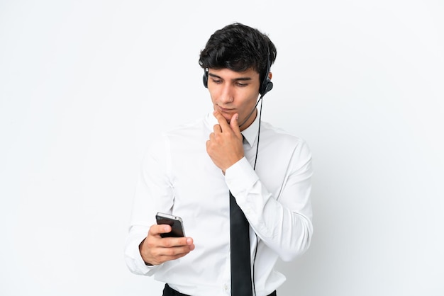 Homem de telemarketing trabalhando com um fone de ouvido isolado no fundo branco pensando e enviando uma mensagem